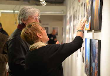 photography teacher looking at photographs on the wall with a student